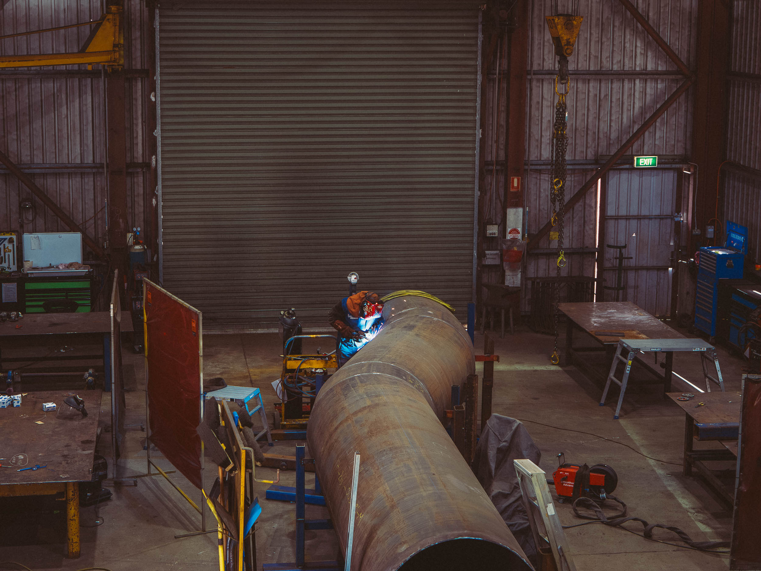 Welder working on large pipe inside Tamar hydro's workshop